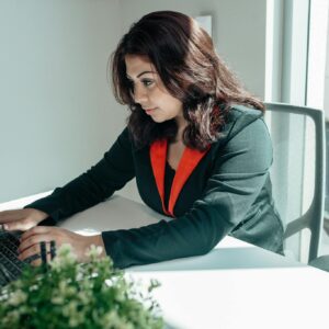 Focused woman working on a laptop in a bright modern office setting.