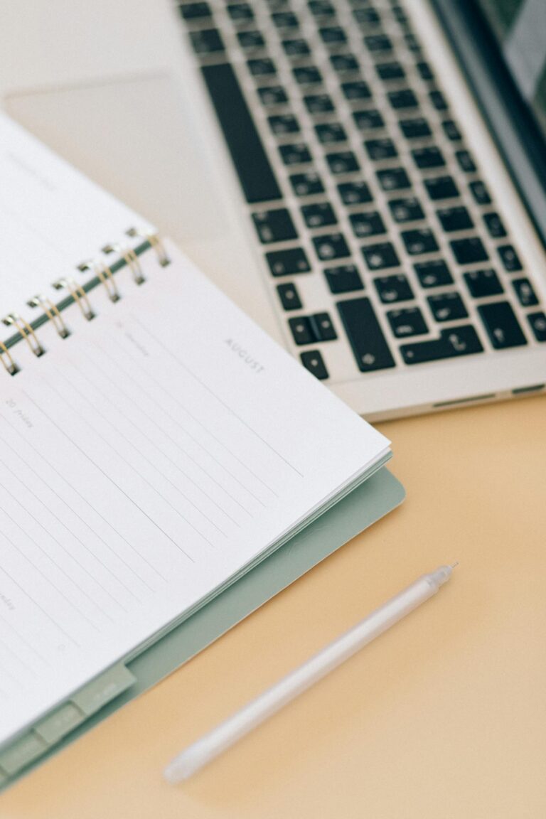 Open notebook next to a laptop and pen on a desk, ideal for business and planning.
